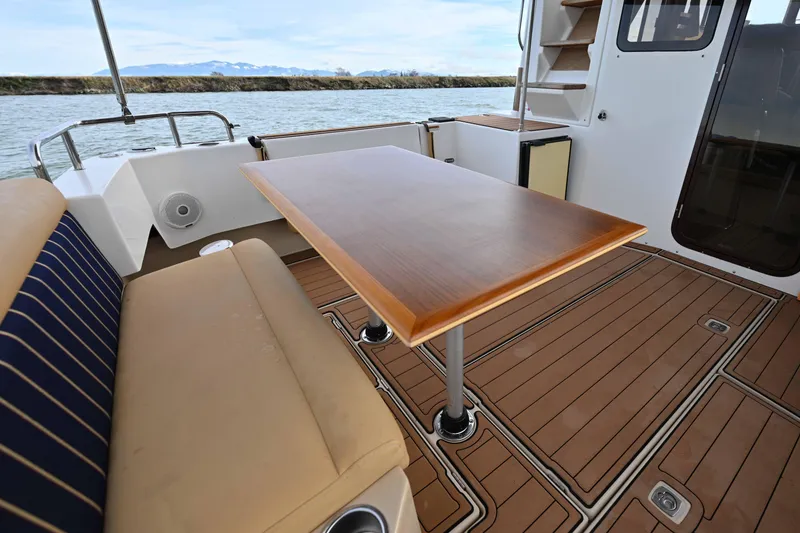 Slide: The Image of 2014 Ranger Tug R-31 CB boat deck with seating and wooden table. - 44