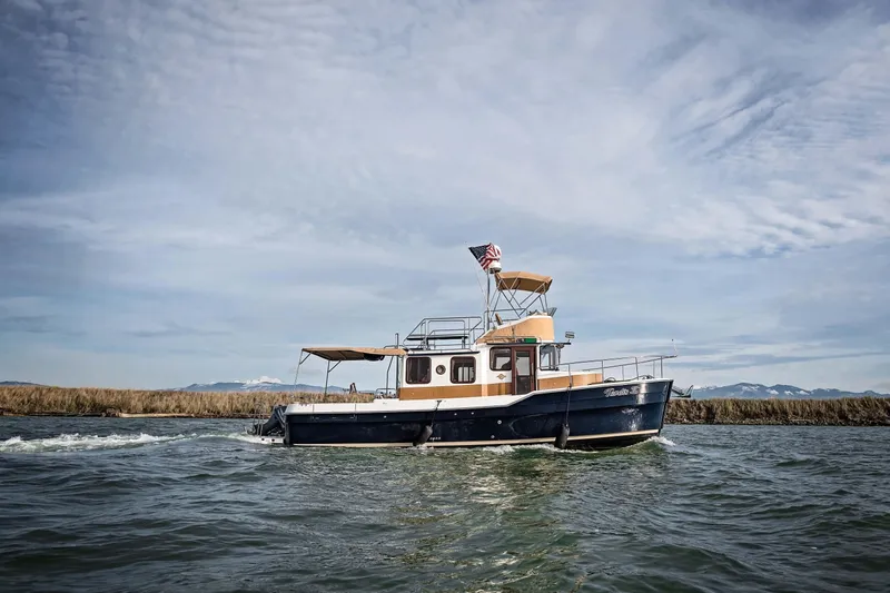 Slide: The Image of 2014 Ranger Tug R-31 CB cruising on open water under a cloudy sky. - 57