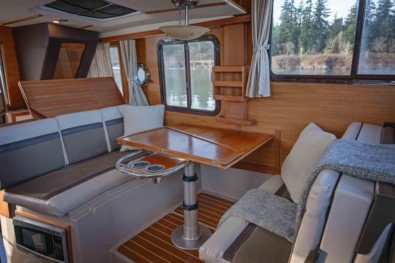 Slide: The Image of Interior of 2014 Ranger Tug R-31 CB with cozy seating and wooden table. - 6