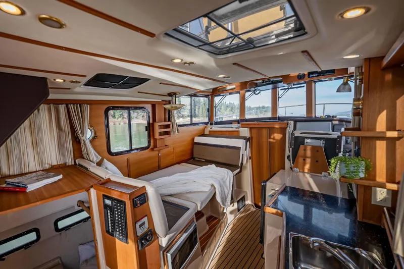 Slide: The Image of Interior of 2014 Ranger Tug R-31 CB, featuring cozy seating and wooden finishes. - 7