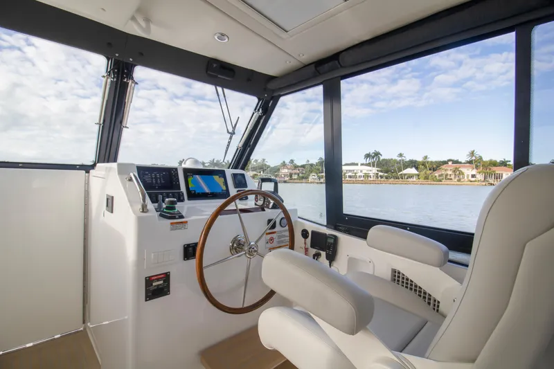 Slide: The Image of 2025 MJM 38 X boat with covered engines, docked by a scenic waterfront. - 8