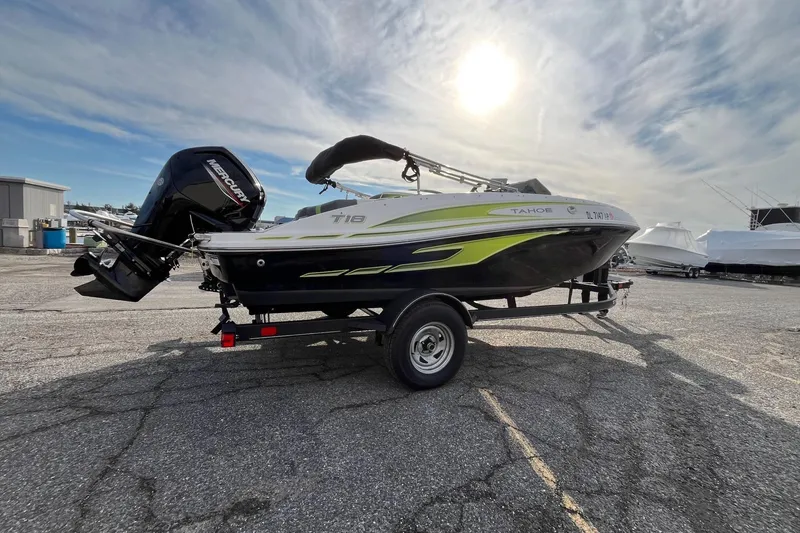 The Image of 2023 Tahoe T18 boat on trailer under sunny sky, featuring sleek design and Mercury outboard motor. - 0