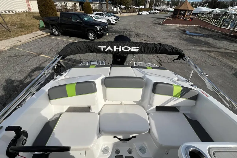 Slide: The Image of 2023 Tahoe T18 boat interior with cushioned seating and steering wheel, parked near vehicles. - 6