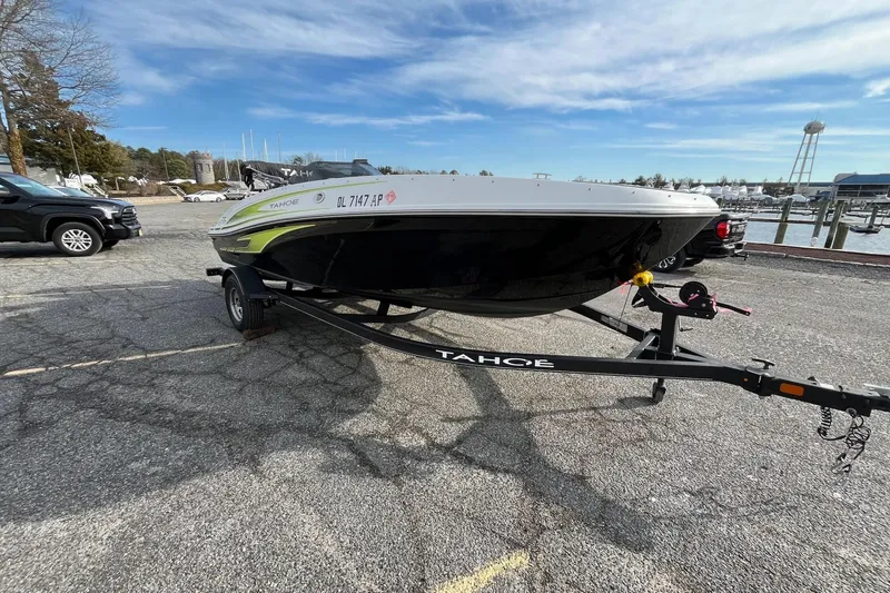 Slide: The Image of 2023 Tahoe T18 boat on trailer in marina parking lot under blue sky. - 8