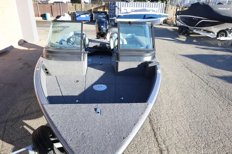 Slide: The Image of 2026 Lund 1775 Impact XS Sport boat with dual windshields, parked outdoors. - 10