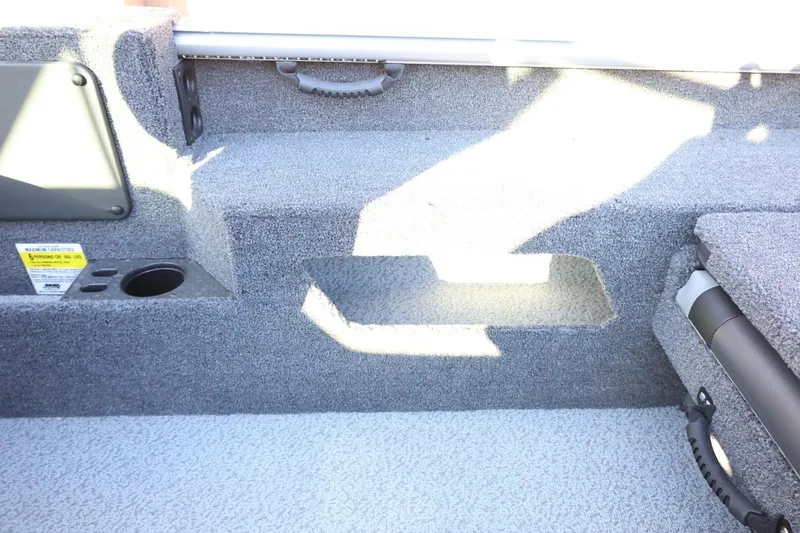 Slide: The Image of 2026 Lund 1775 Impact XS Sport boat interior with gray carpet and storage compartments. - 34