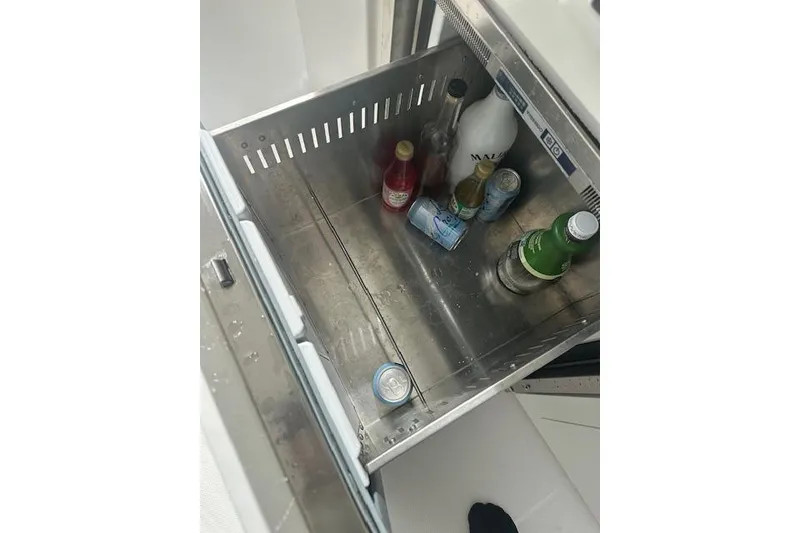 Slide: The Image of Open stainless steel drawer with assorted beverages on a 2022 Regal 38 SAV boat. - 44