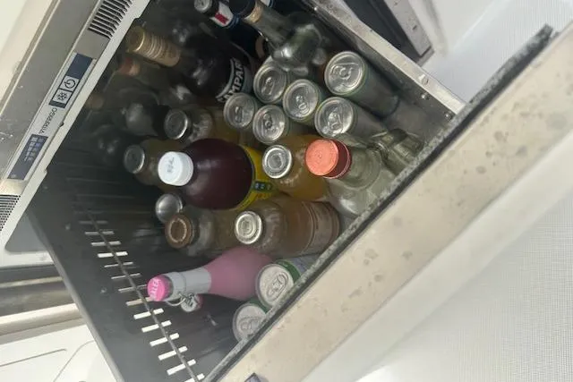 Slide: The Image of Refrigerator stocked with assorted beverages on a 2022 Regal 38 SAV boat. - 46