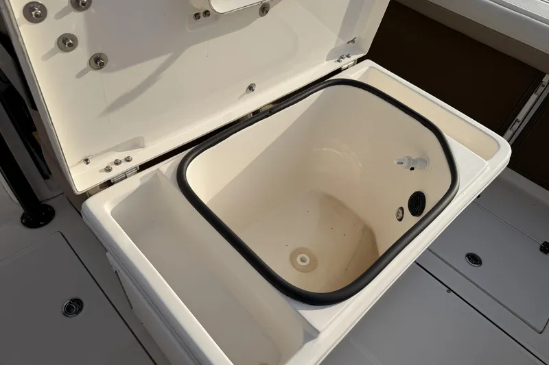 Slide: The Image of 2024 Sea Born SX239 Offshore boat storage compartment, open lid, white interior. - 28