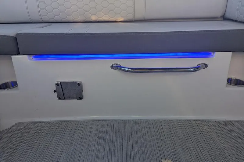 Slide: The Image of 2021 Sea Ray SDX 270 Outboard interior with blue LED lighting and cushioned seating. - 11