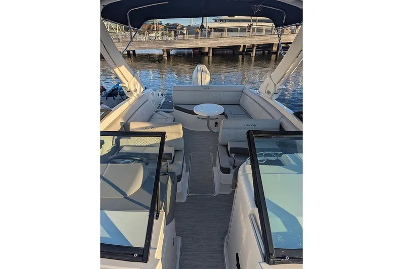 Slide: The Image of 2021 Sea Ray SDX 270 Outboard boat interior with seating and table, docked by the water. - 36