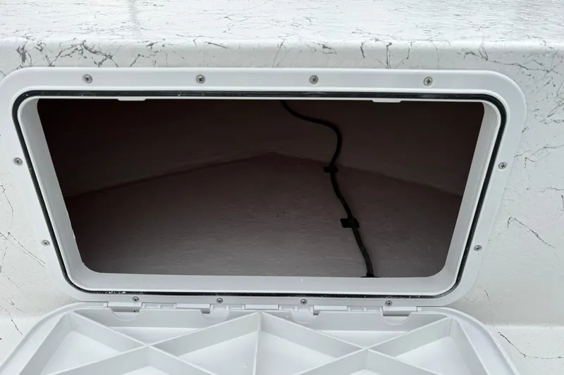 Slide: The Image of Open storage compartment on a 2026 Coastal Skiff 171 boat, featuring a white interior. - 11