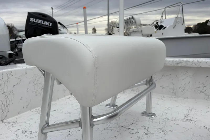 Slide: The Image of White cushioned seat on 2026 Coastal Skiff 171 boat, with Suzuki motor in background. - 6