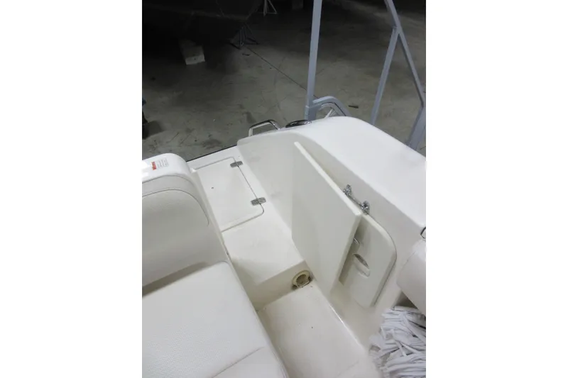 Slide: The Image of 2011 Pursuit C 230 Center Console boat interior with white seating and storage compartment. - 27
