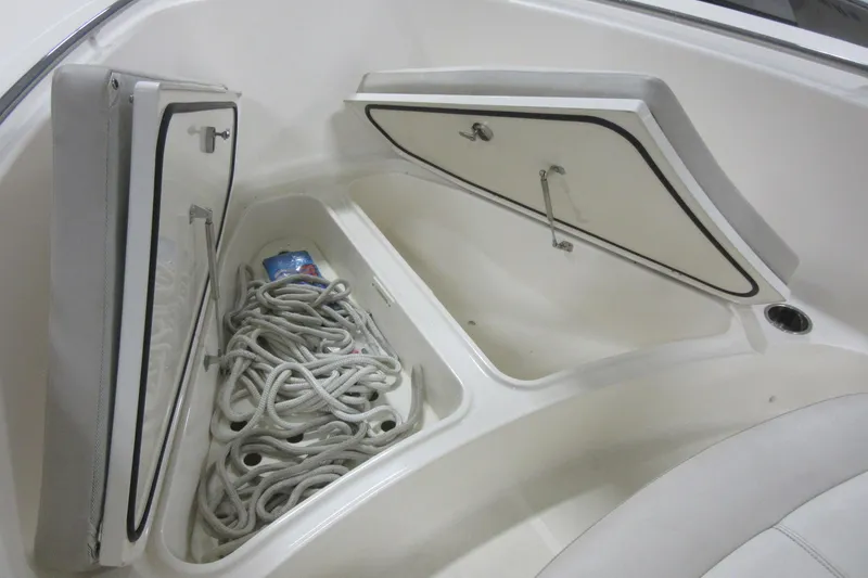 Slide: The Image of 2011 Pursuit C 230 Center Console boat storage compartments with rope and drink can. - 5