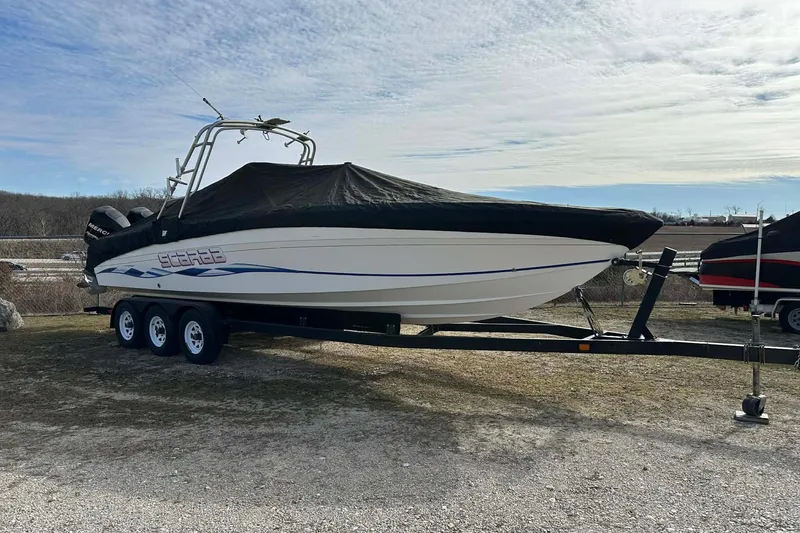 The Image of 1995 Wellcraft 302 Scarab Sport boat on trailer, covered, parked outdoors. - 0