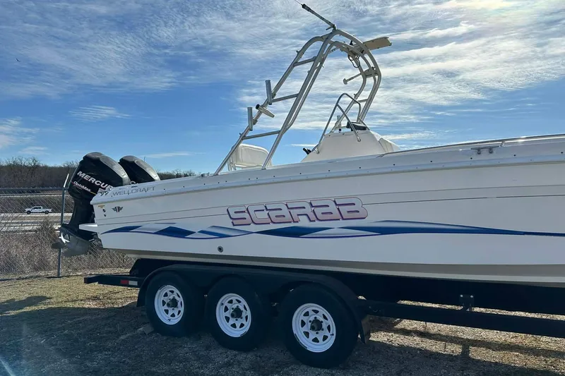 Slide: The Image of 1995 Wellcraft 302 Scarab Sport boat on trailer, featuring dual Mercury engines. - 2