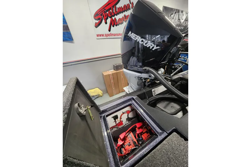Slide: The Image of 2026 Warrior V208 boat with Mercury engine, open storage compartment, and Spellman's Marine signage. - 13