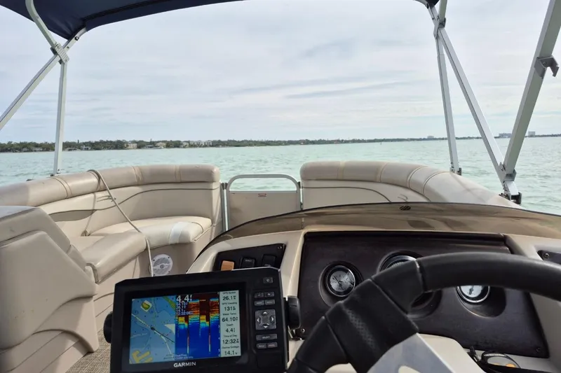 Slide: The Image of 2015 Bennington 24SSRX pontoon boat interior with Garmin navigation system on calm water. - 28