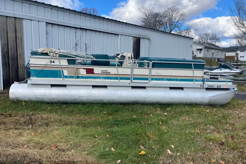 The Image of 1989 Harris FloteBote 240 Classic pontoon boat on grass near a metal building. - 0