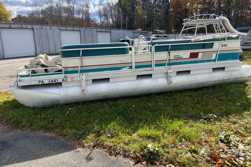 Slide: The Image of 1989 Harris FloteBote 240 Classic pontoon boat on grass near storage units. - 6