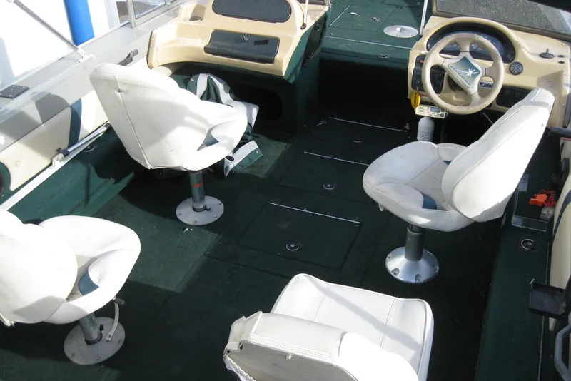 Slide: The Image of Interior of a 1999 Starcraft Pro-Elite 2000 boat with white seating and green flooring. - 7