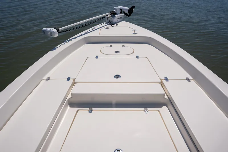 Slide: The Image of 2018 Pathfinder 2400 TRS boat deck with storage compartments and trolling motor on calm water. - 18