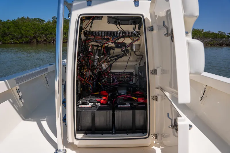 Slide: The Image of 2018 Pathfinder 2400 TRS boat electrical compartment with batteries and wiring, open on a sunny day. - 29