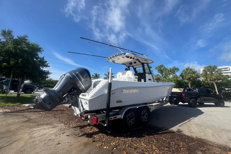 Slide: The Image of 2021 Everglades 295 Center Console boat on trailer, parked under a clear blue sky. - 1