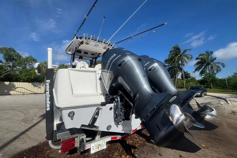 Slide: The Image of 2021 Everglades 295 Center Console boat with dual Yamaha engines, parked outdoors. - 2