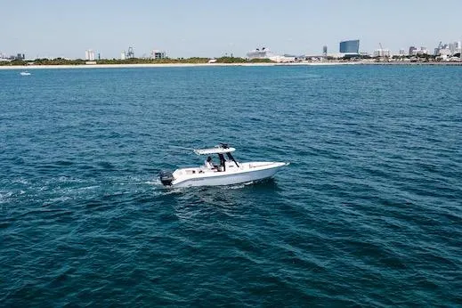 Slide: The Image of 2021 Everglades 295 Center Console boat cruising on open water near city skyline. - 59