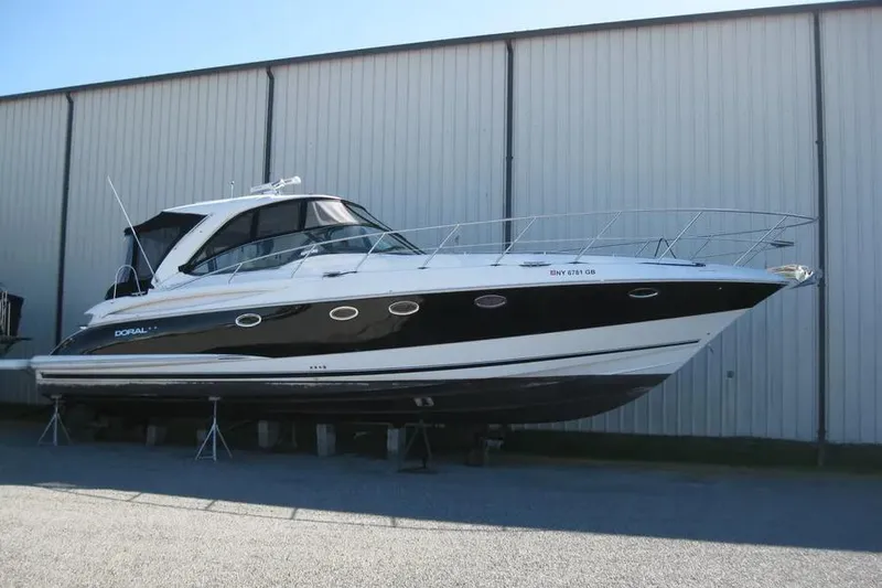 Slide: The Image of 2008 Doral Alegria yacht on stands, black and white exterior, docked near a warehouse. - 2