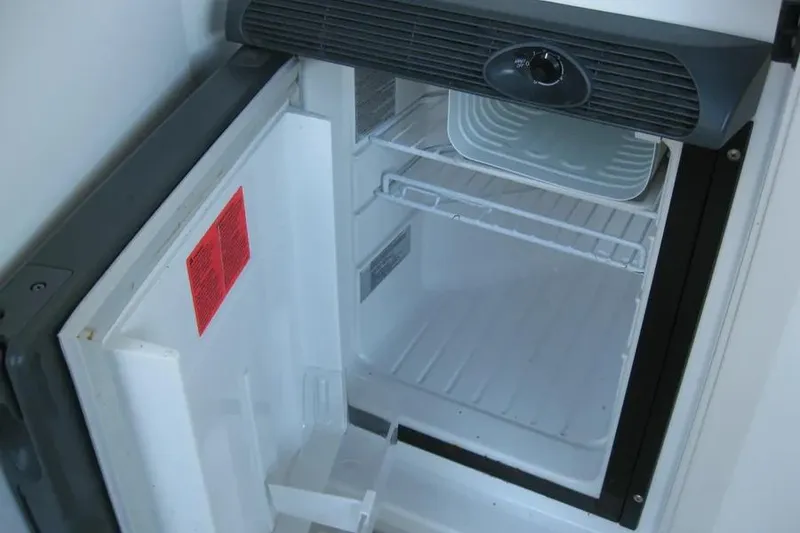 Slide: The Image of Open refrigerator door in a 2008 Doral Alegria boat, showing empty interior. - 21