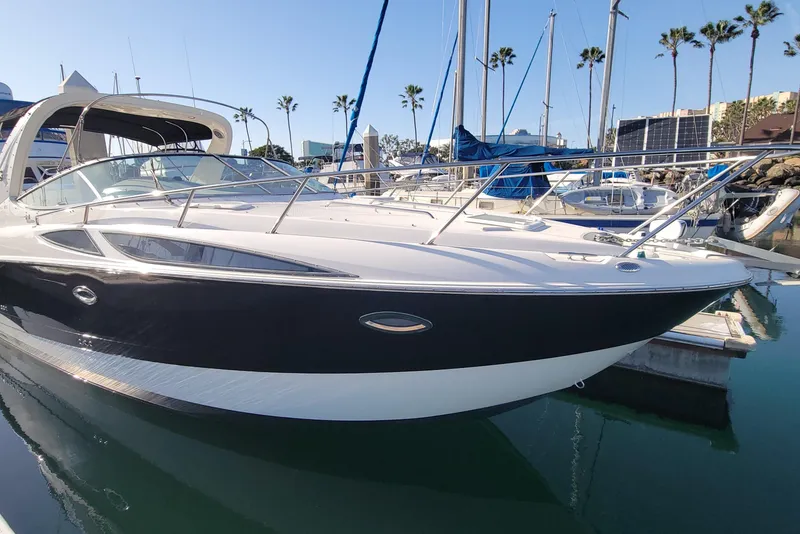The Image of 2011 Bayliner 315 Cruiser docked at marina, surrounded by sailboats and palm trees. - 0