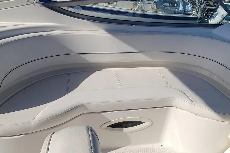 Slide: The Image of 2011 Bayliner 315 Cruiser interior seating with white upholstery and window view. - 10