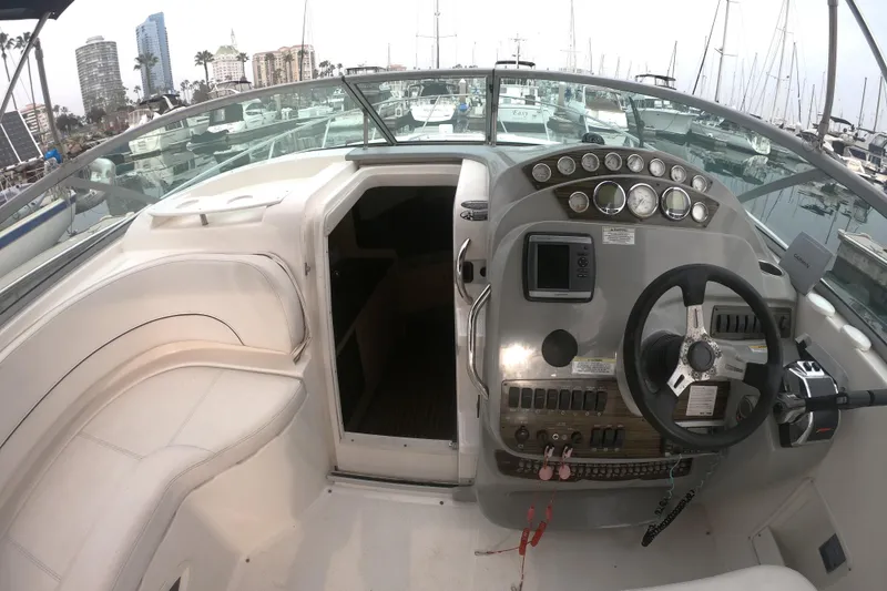 Slide: The Image of 2011 Bayliner 315 Cruiser cockpit with steering wheel, control panel, and marina view. - 13