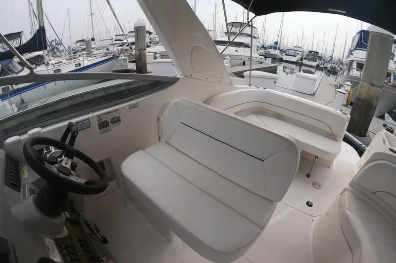 Slide: The Image of 2011 Bayliner 315 Cruiser interior with white seating, docked at a marina. - 15
