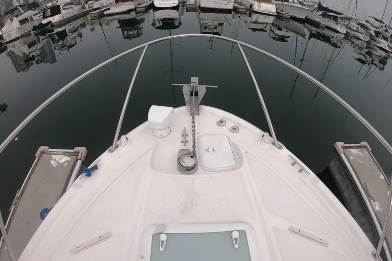 Slide: The Image of 2011 Bayliner 315 Cruiser bow view at marina, surrounded by docked boats. - 19