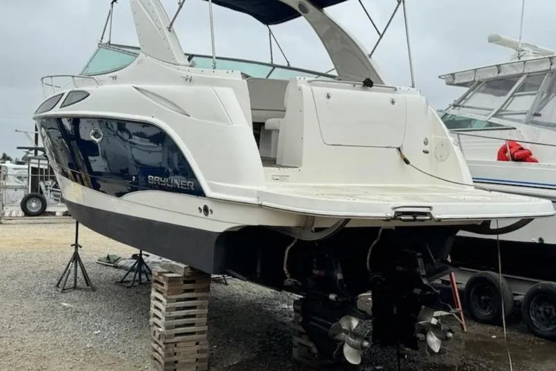 Slide: The Image of 2011 Bayliner 315 Cruiser boat on stands, rear view, in a marina setting. - 25