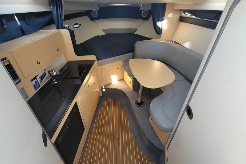 Slide: The Image of 2011 Bayliner 315 Cruiser interior with kitchenette, seating area, and wood flooring. - 28