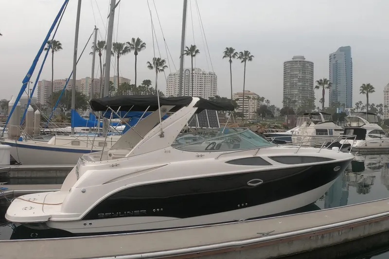 Slide: The Image of 2011 Bayliner 315 Cruiser docked in marina, city skyline in background. - 3