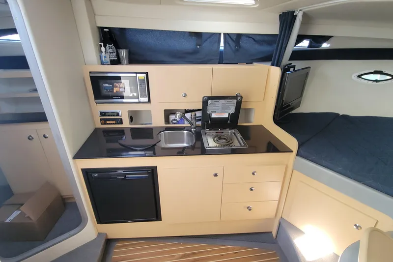 Slide: The Image of 2011 Bayliner 315 Cruiser interior with kitchenette, microwave, sink, and bed area. - 30