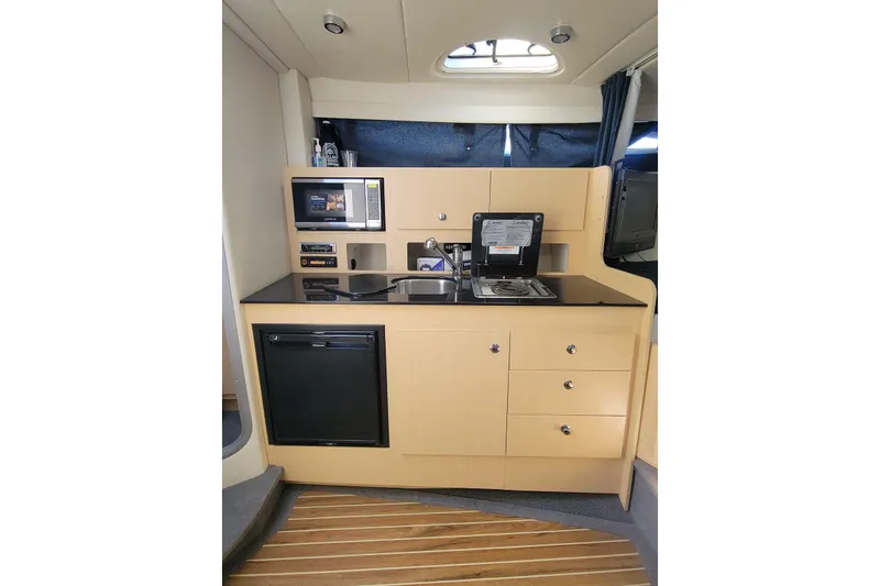 Slide: The Image of 2011 Bayliner 315 Cruiser interior kitchen with microwave, sink, and compact fridge. - 31