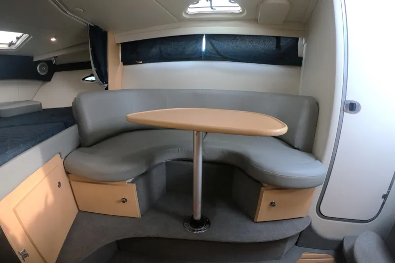 Slide: The Image of 2011 Bayliner 315 Cruiser interior with gray seating and wooden table. - 34