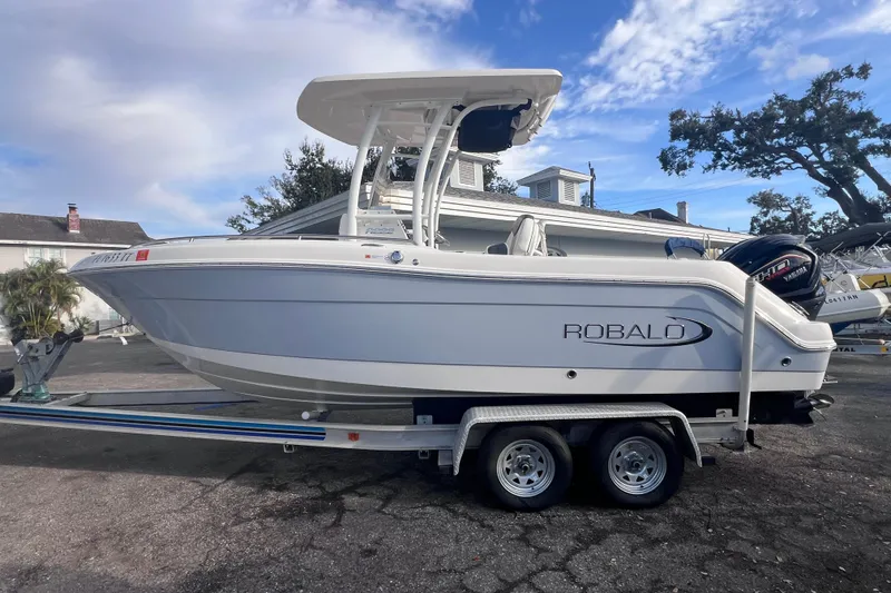 Slide: The Image of 2023 Robalo R222 Explorer boat on trailer, parked outdoors under a cloudy sky. - 8