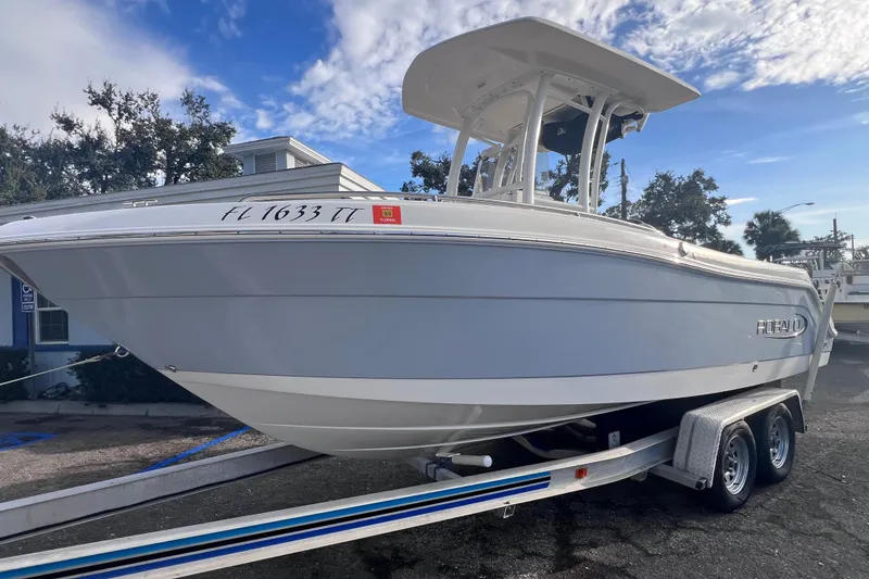 Slide: The Image of 2023 Robalo R222 Explorer boat on trailer, parked outdoors under a partly cloudy sky. - 9