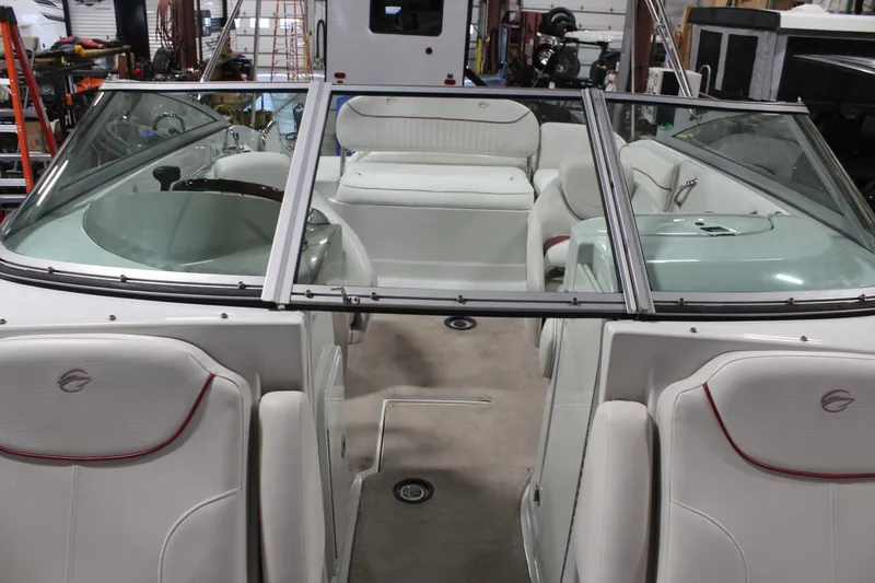 Slide: The Image of 2008 Crownline 220 EX boat interior with white seating and windshield in a garage setting. - 34