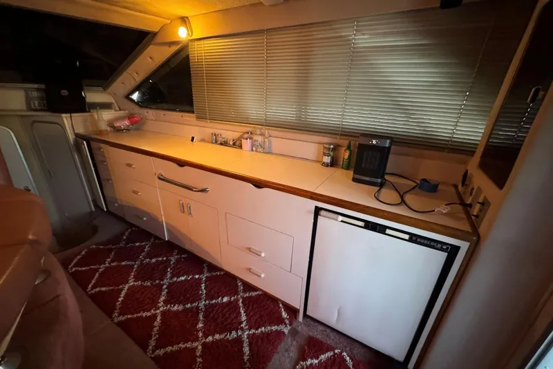 Slide: The Image of 1989 Sea Ray 300 Sedan Bridge interior with kitchenette, featuring cabinets and mini fridge. - 22