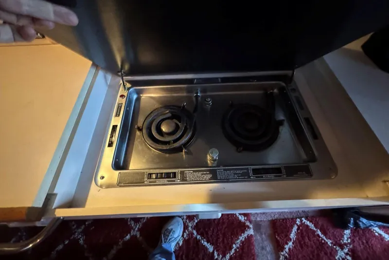 Slide: The Image of 1989 Sea Ray 300 Sedan Bridge stove with two burners, under a lifted cover. - 24