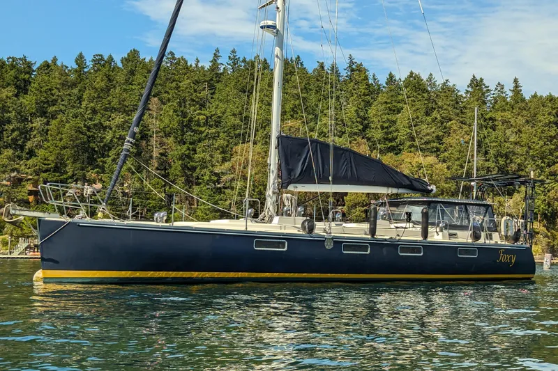 The Image of Sundeer 56 sailboat from 1995 on calm water, surrounded by lush green trees. - 0